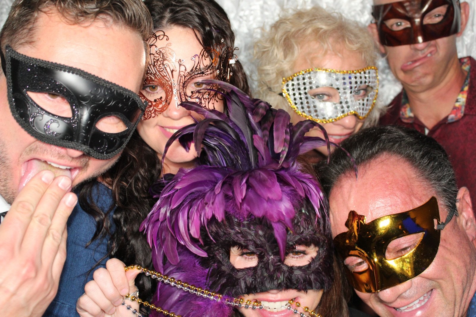 Group of guests in masks with a microphone prop at the photo booth