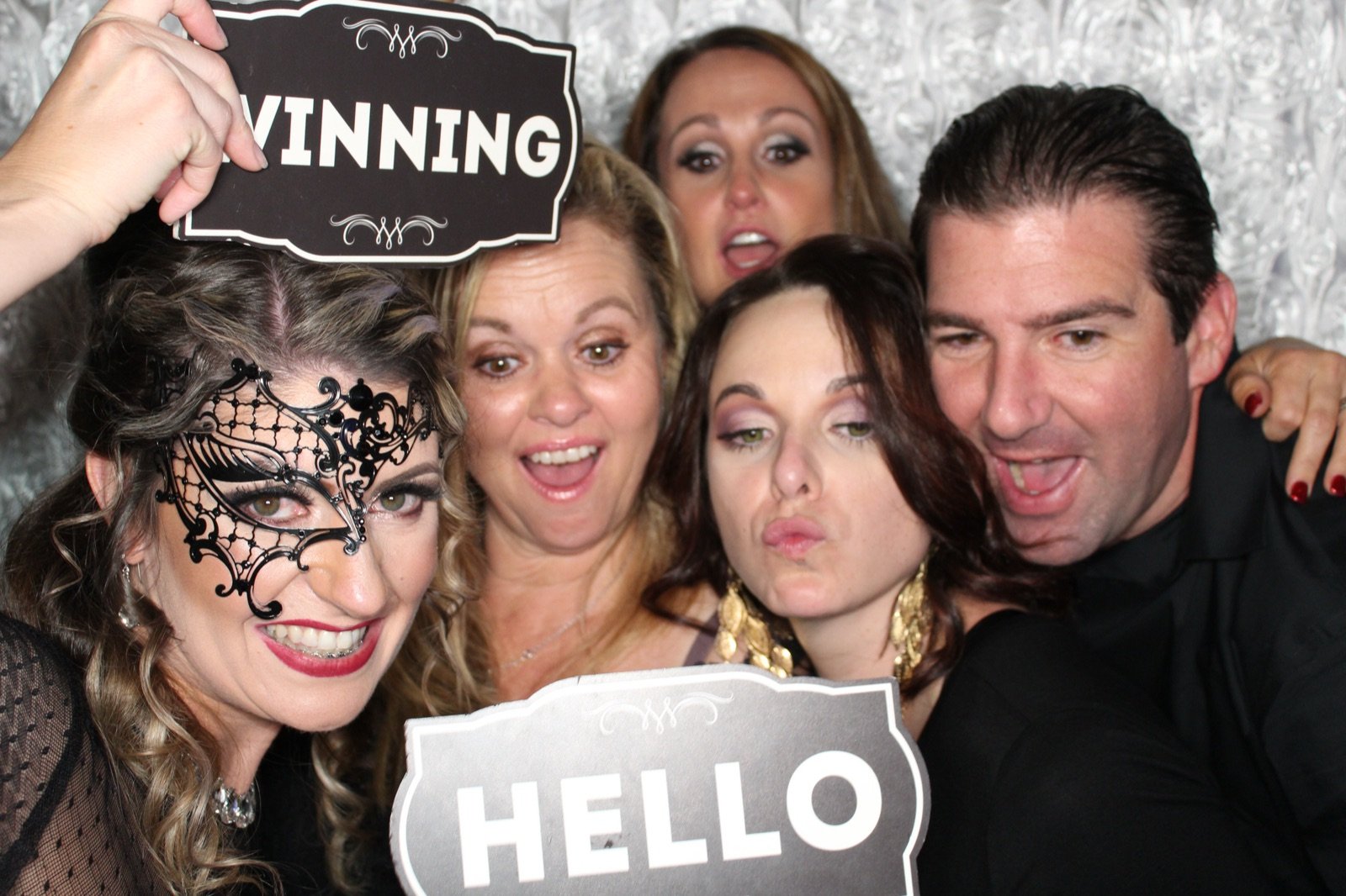Friends in a lace mask with WINNING and HELLO photo booth signs