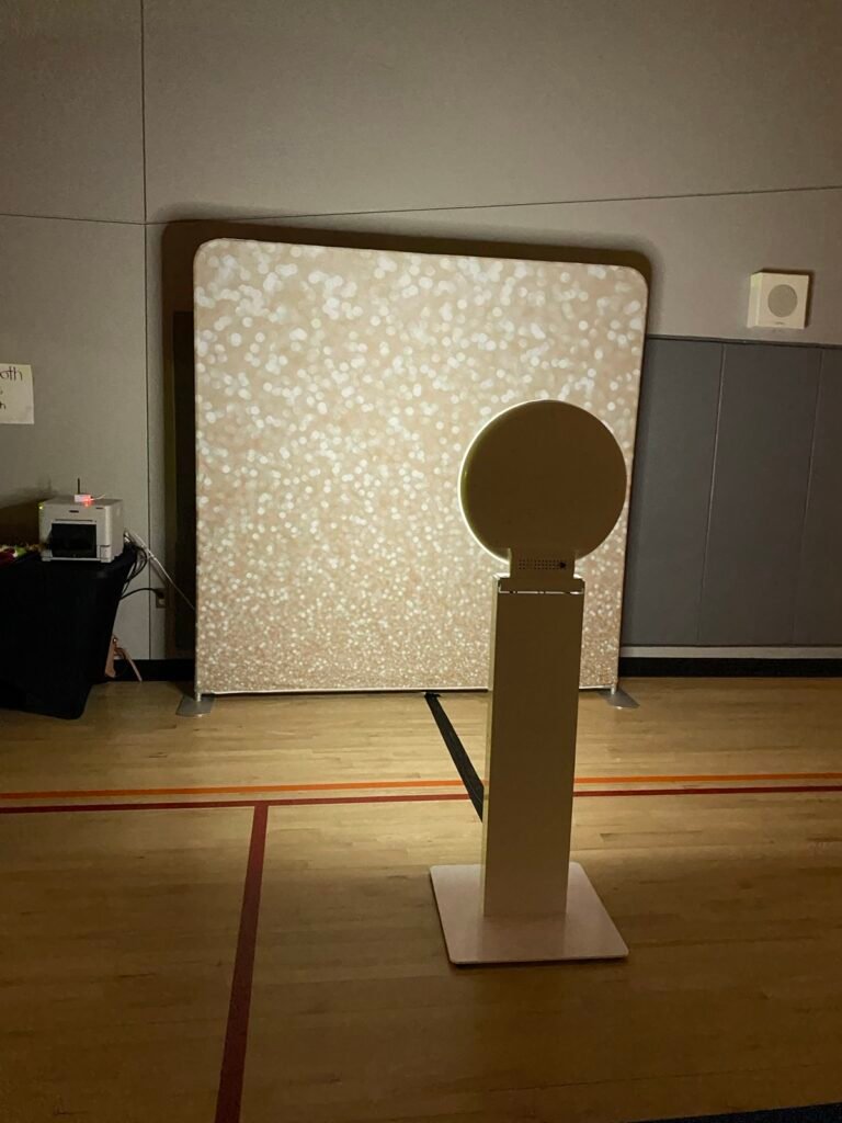 Selfie photo booth with a glitter backdrop at a school dance