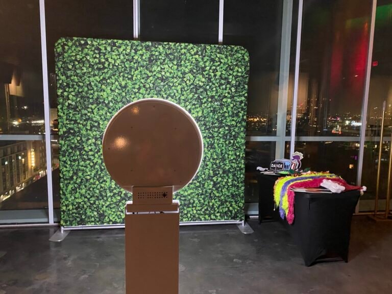 Selfie photo booth in front of a green hedge wall backdrop